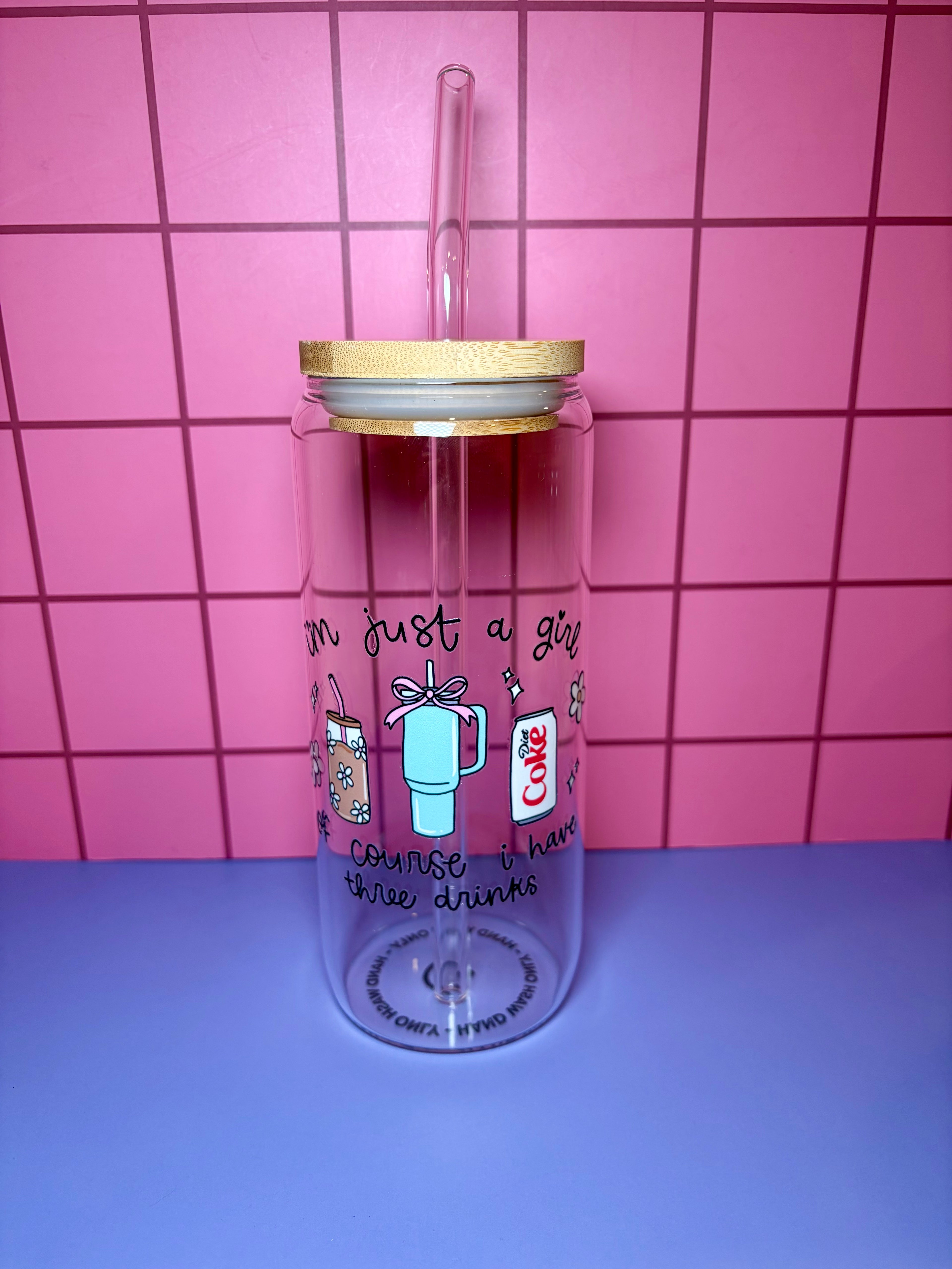 Clear tumbler with straw and lid on a pink tiled background