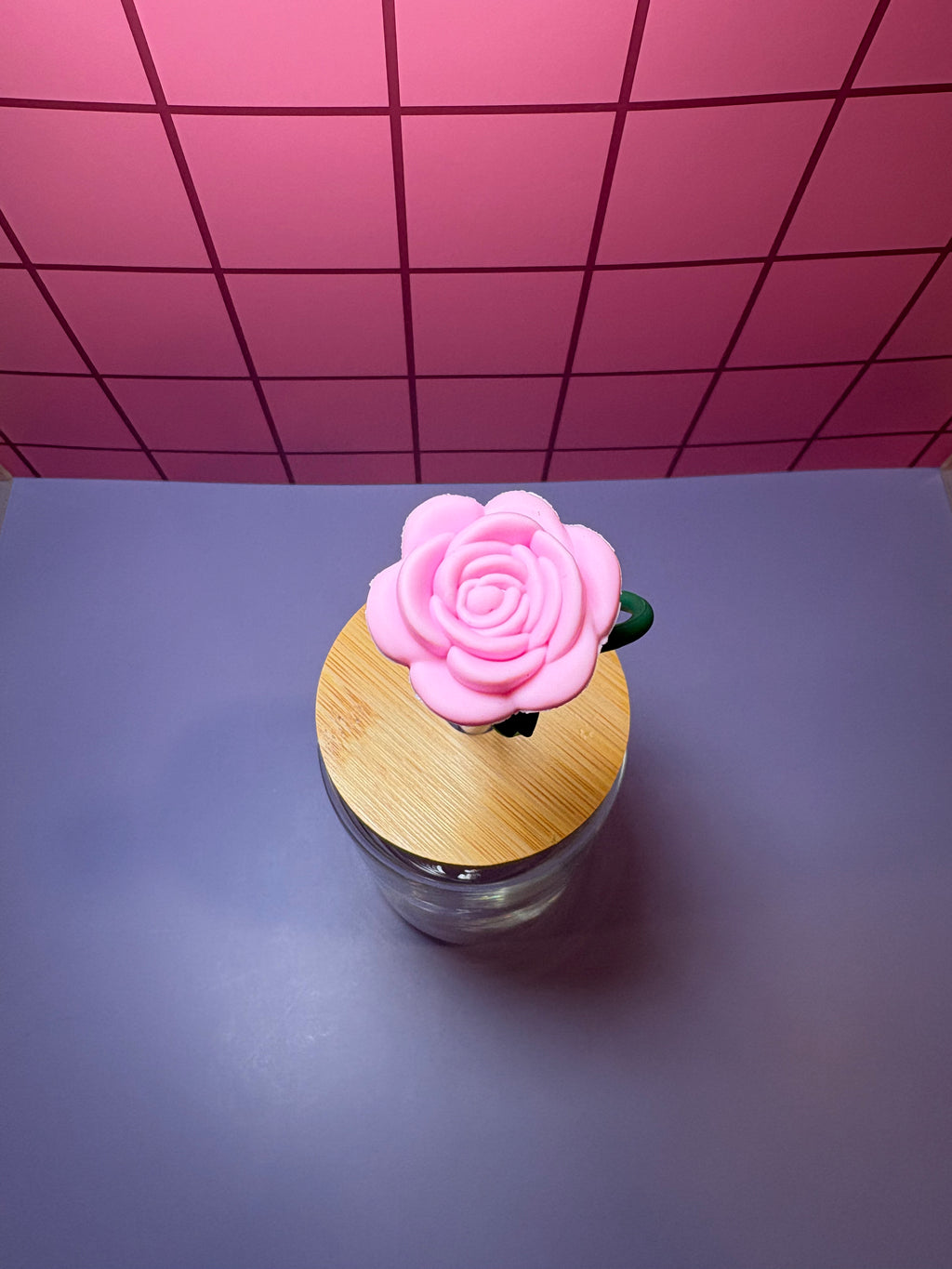 Clear glass bottle with wooden cap and top of pink rose straw topper