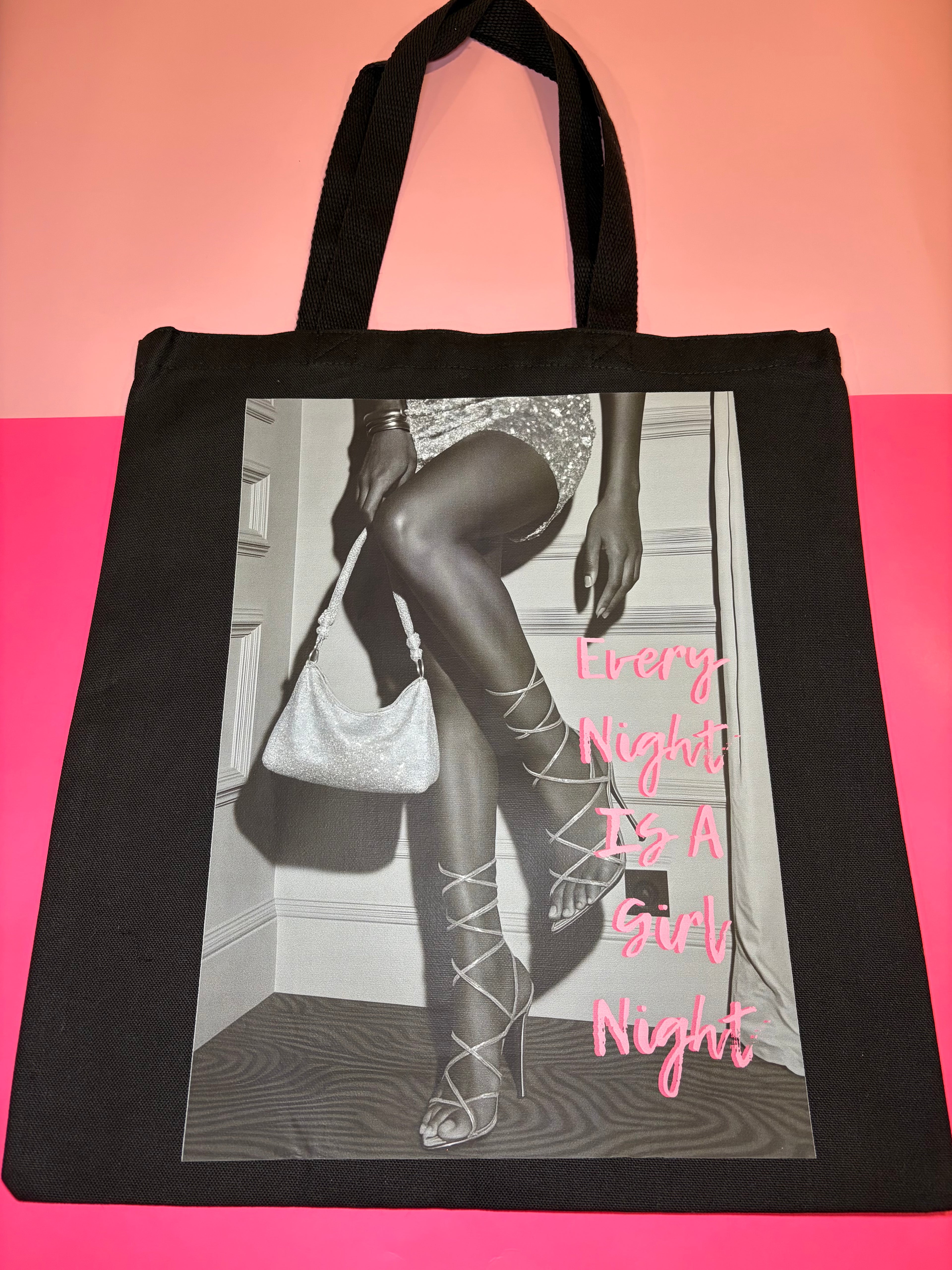 Black tote bag with a graphic of legs in stockings and high heels, pink text 'Every Night Is A Girl Night'.