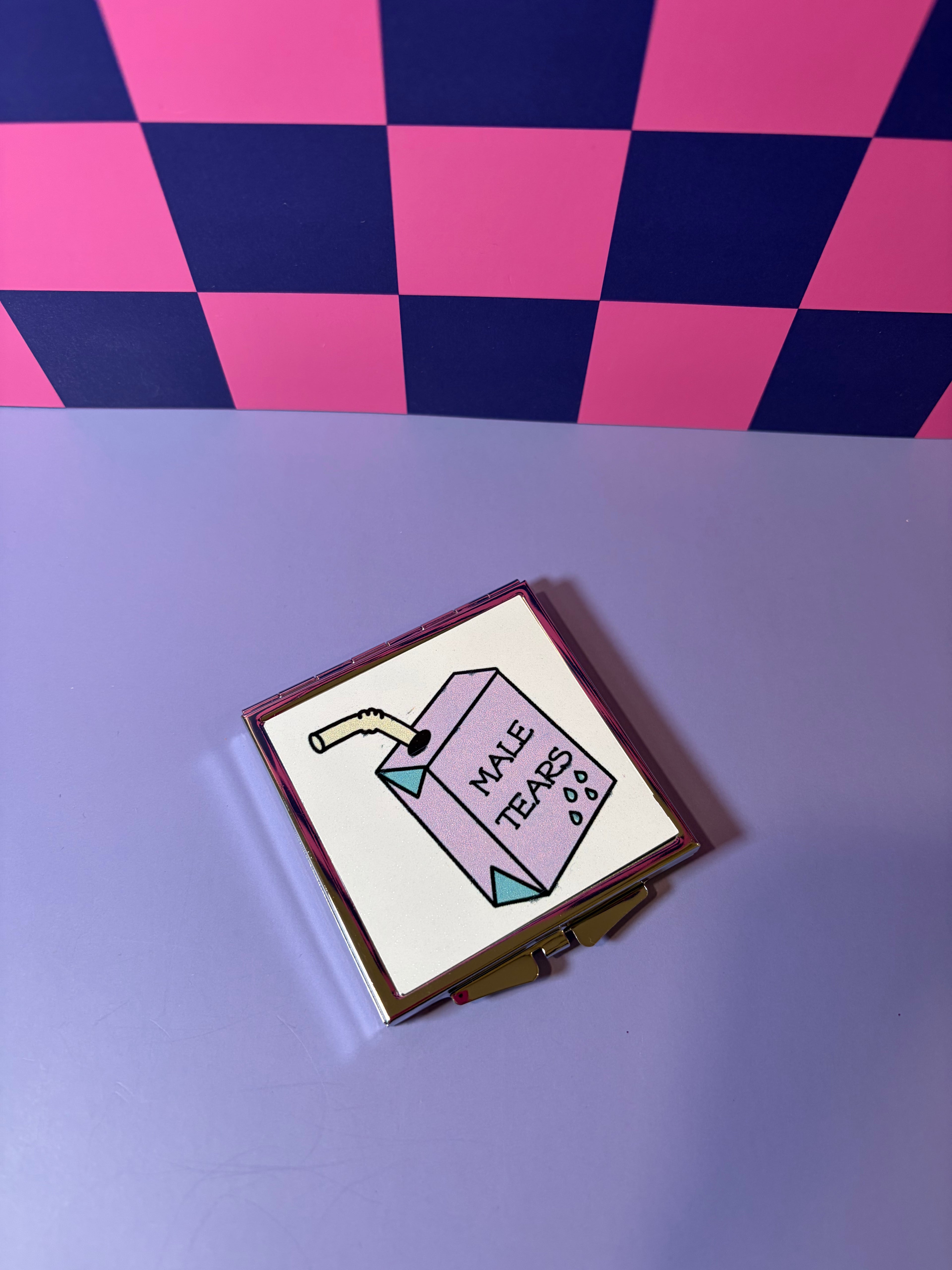 Compact mirror with 'Male Tears' purple juicebox design 