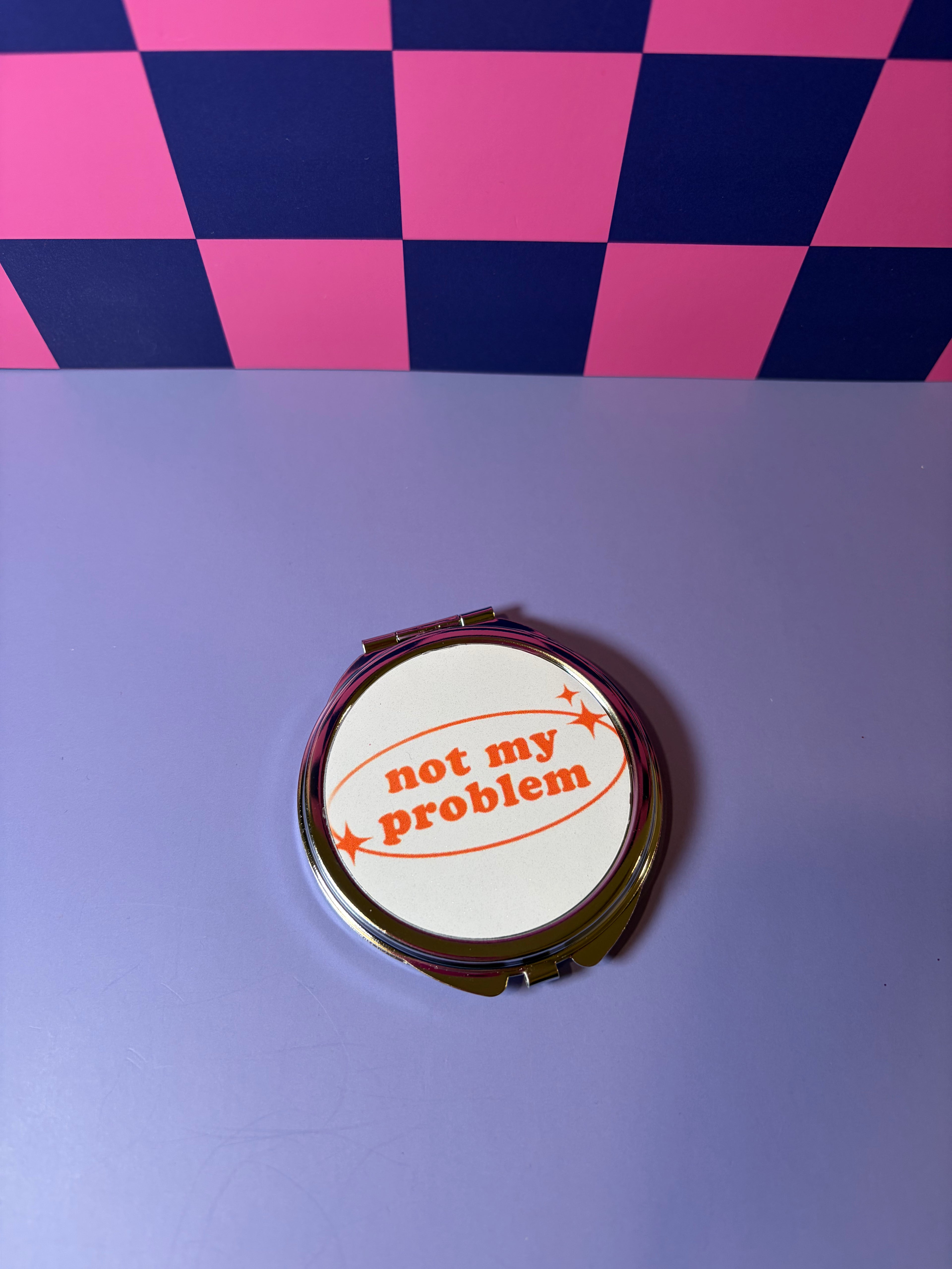 Compact mirror with "Not My Problem" red text and graphic