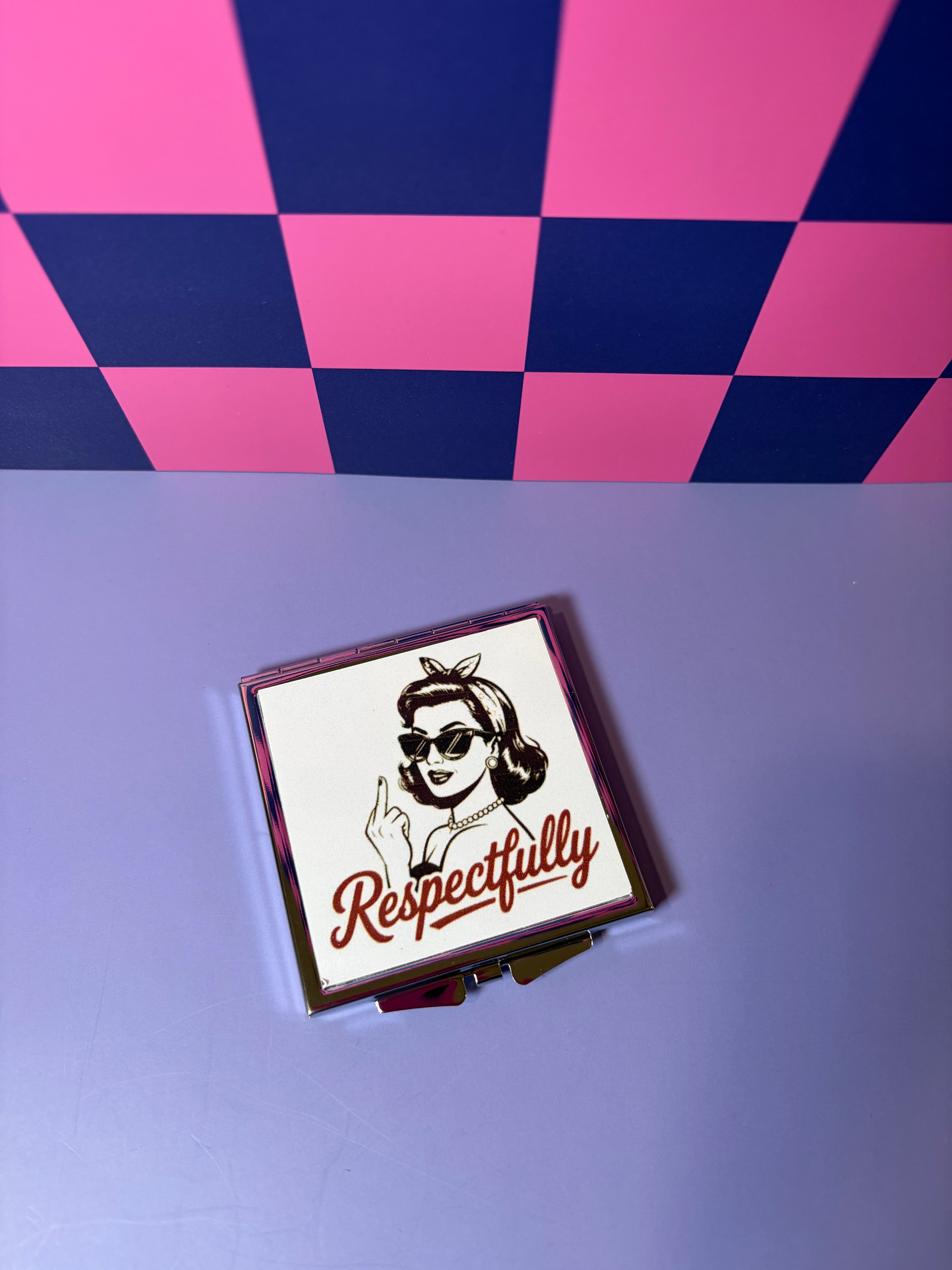 Compact mirror with a design of a woman holding up the middle finger and the word 'Respectfully' 