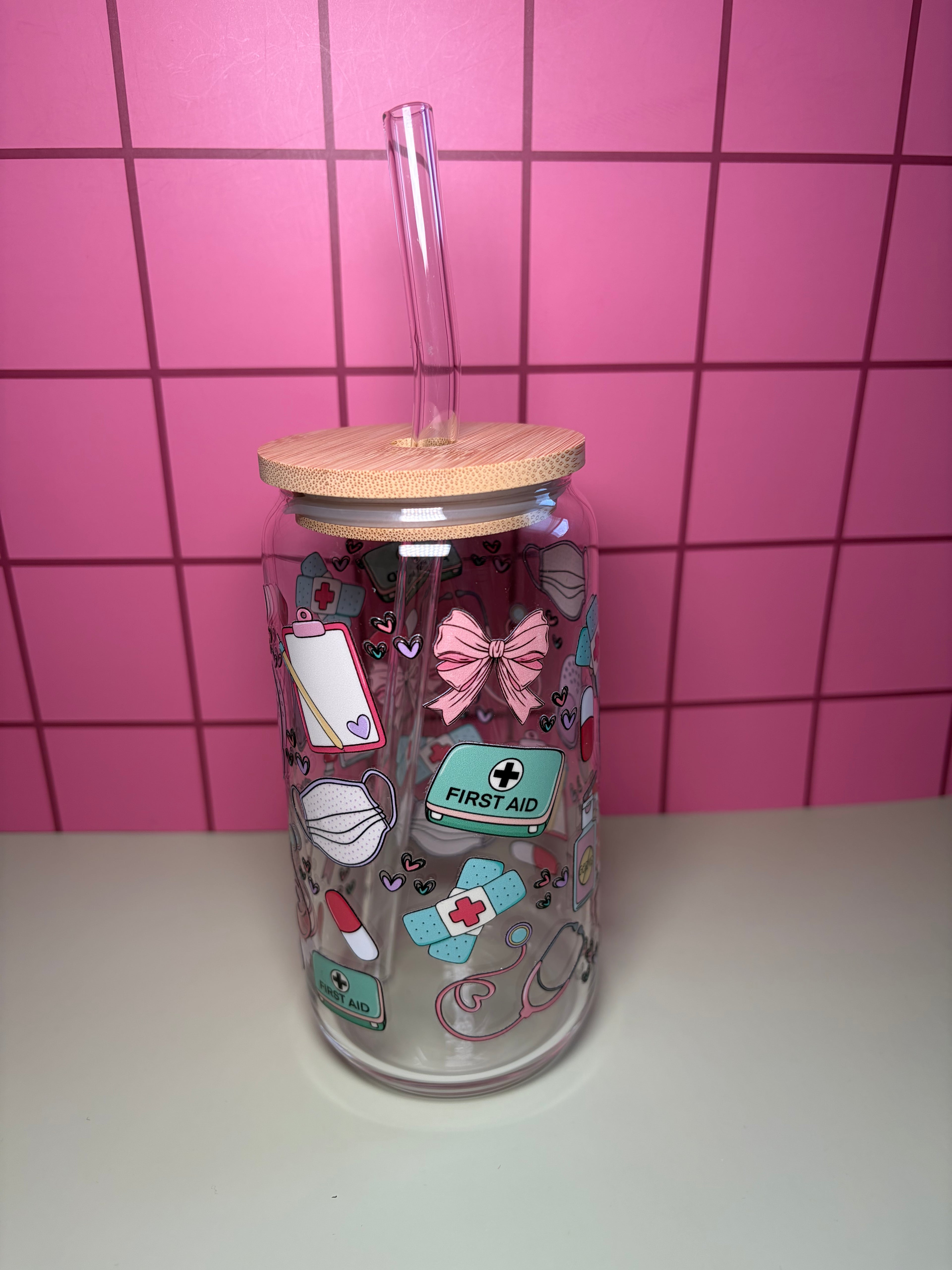 Clear tumbler with wooden lid and colorful nurse themed stickers against a pink tiled wall.