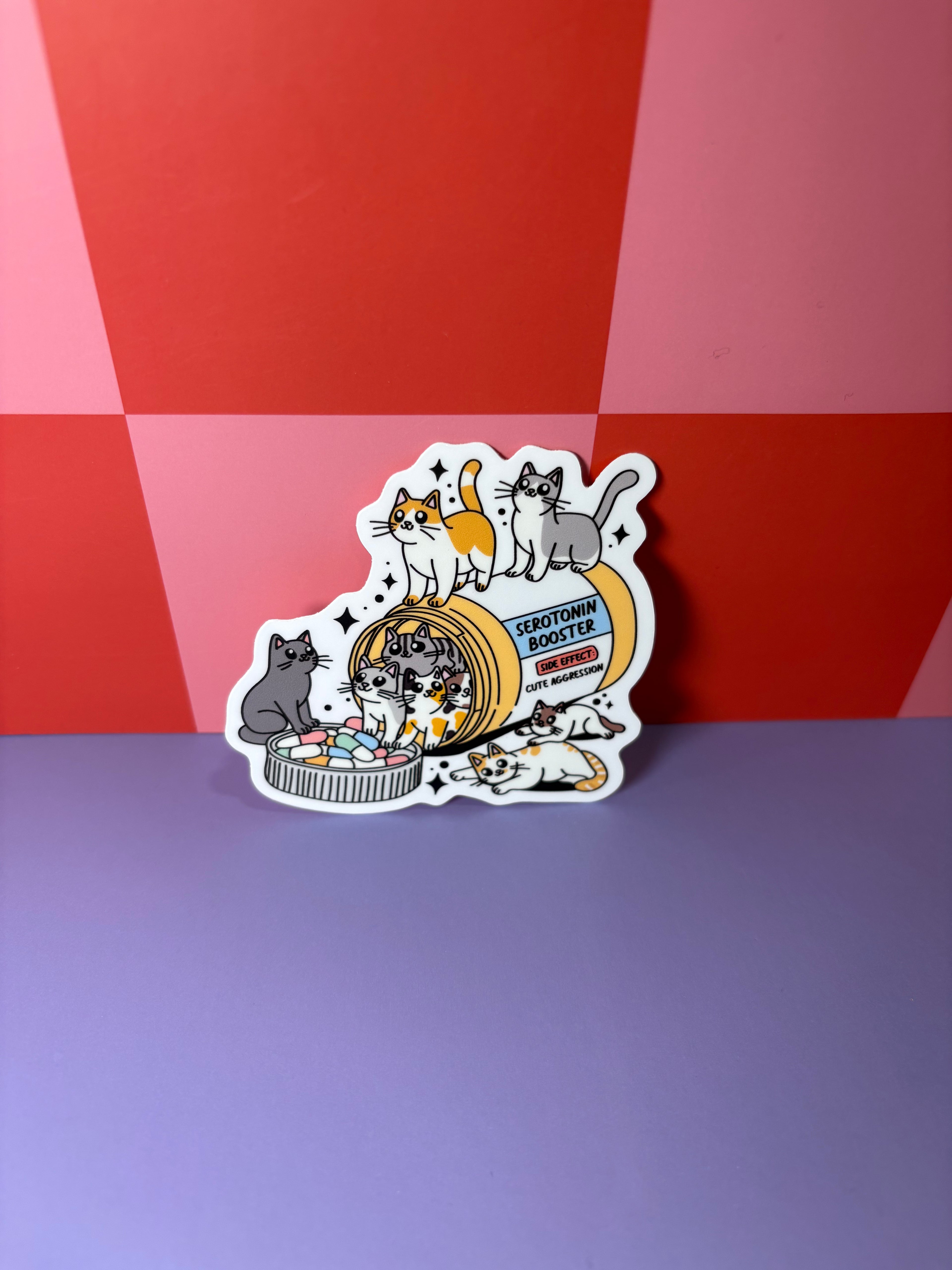Sticker with cartoon cats and a pill bottle labeled "Serotonin Booster"