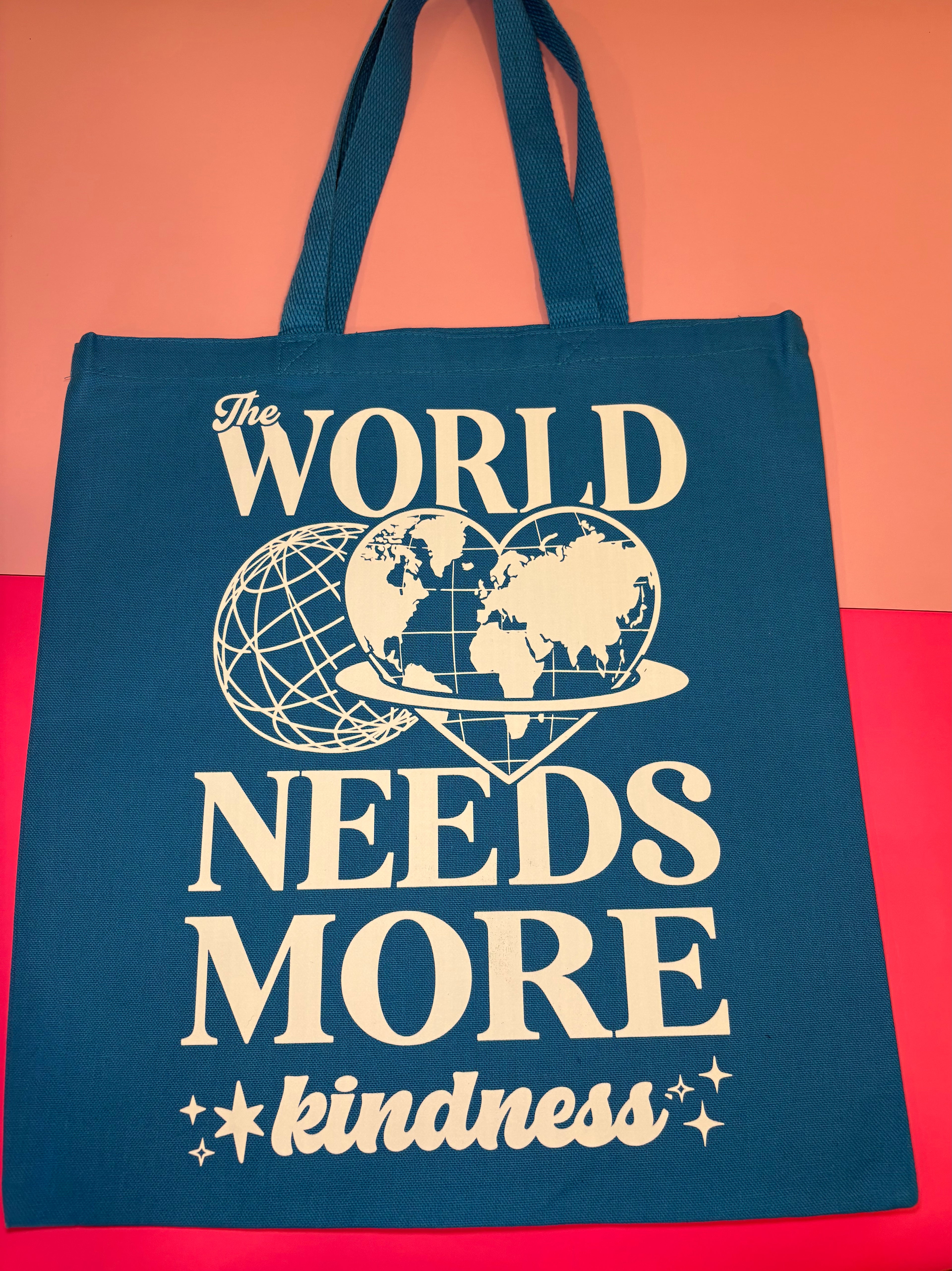 Blue tote with "The World Needs More Kindness" graphic
