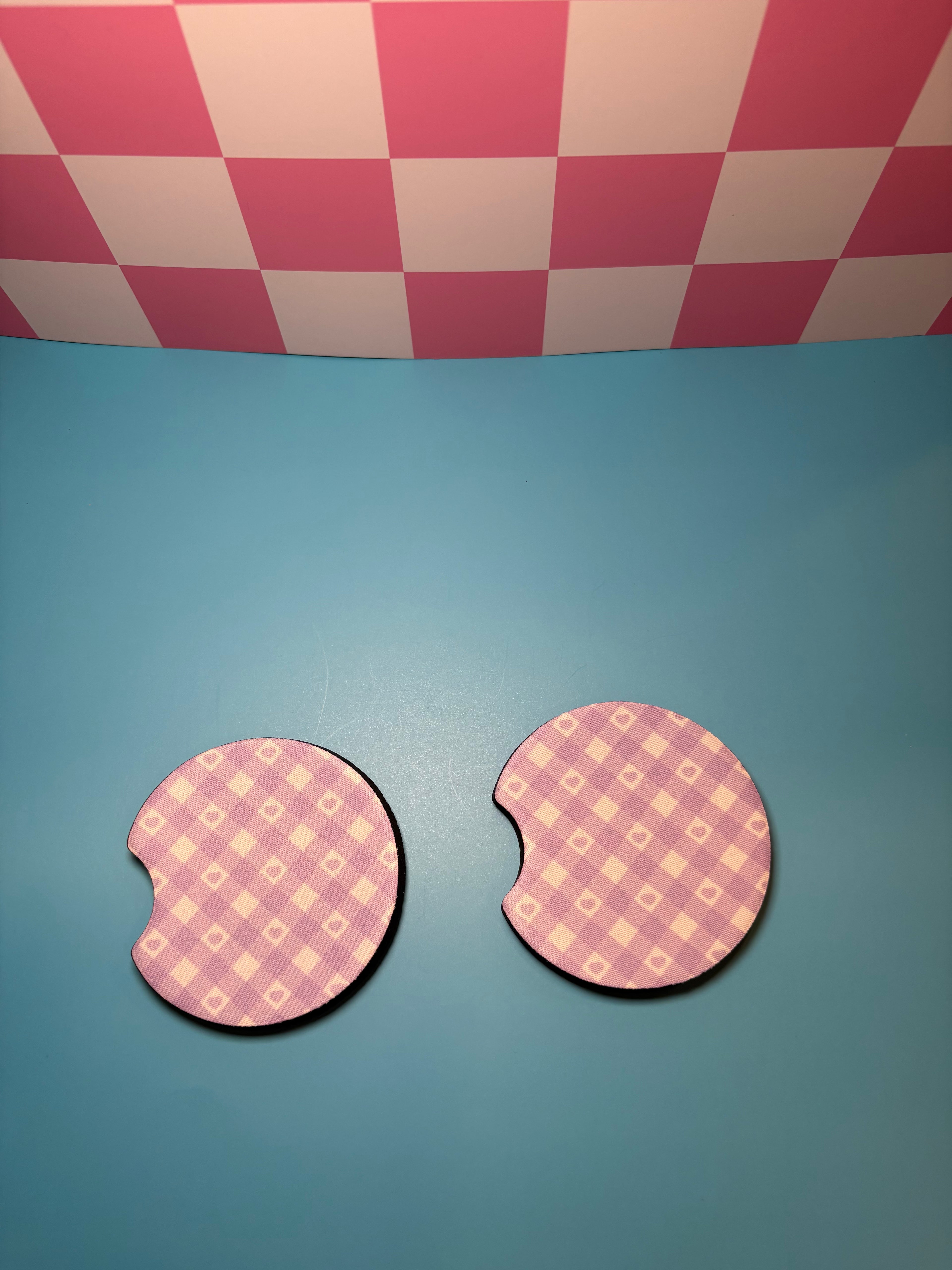Two purple checkered car coasters with hearts