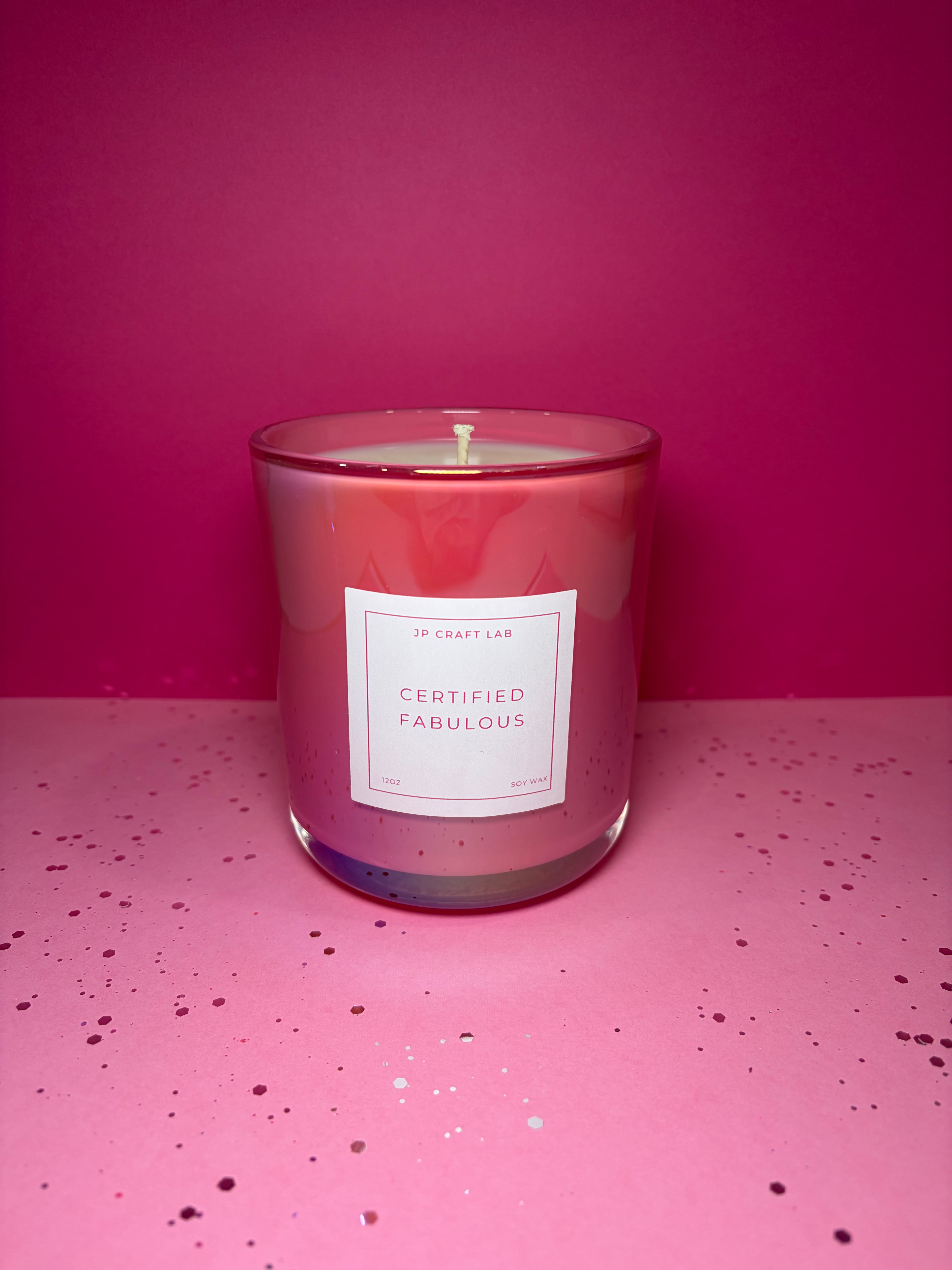 Candle in a pink jar with a label on a pink background