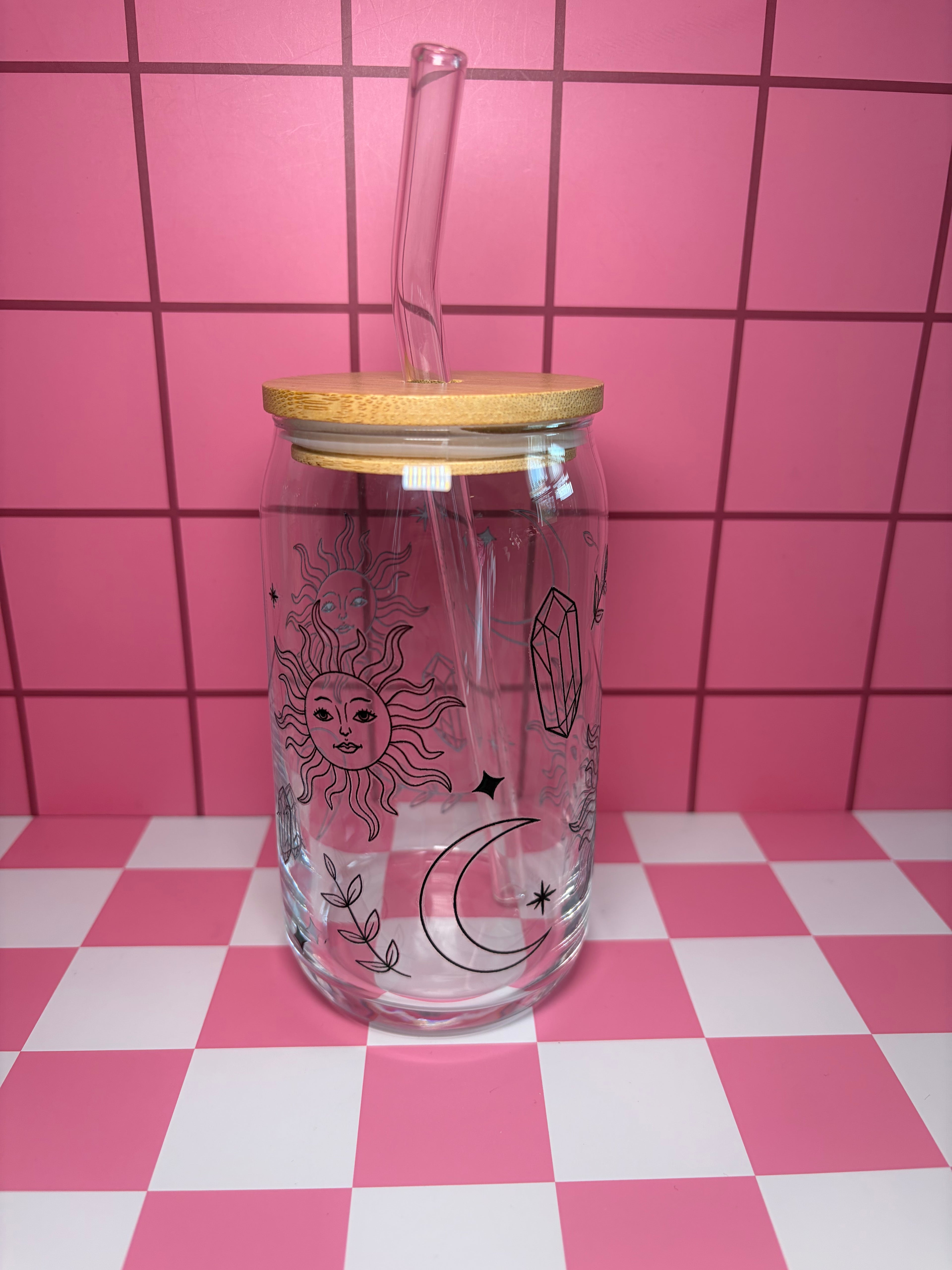 Glass can with wooden lid and straw and sun and moon designs in black sketches