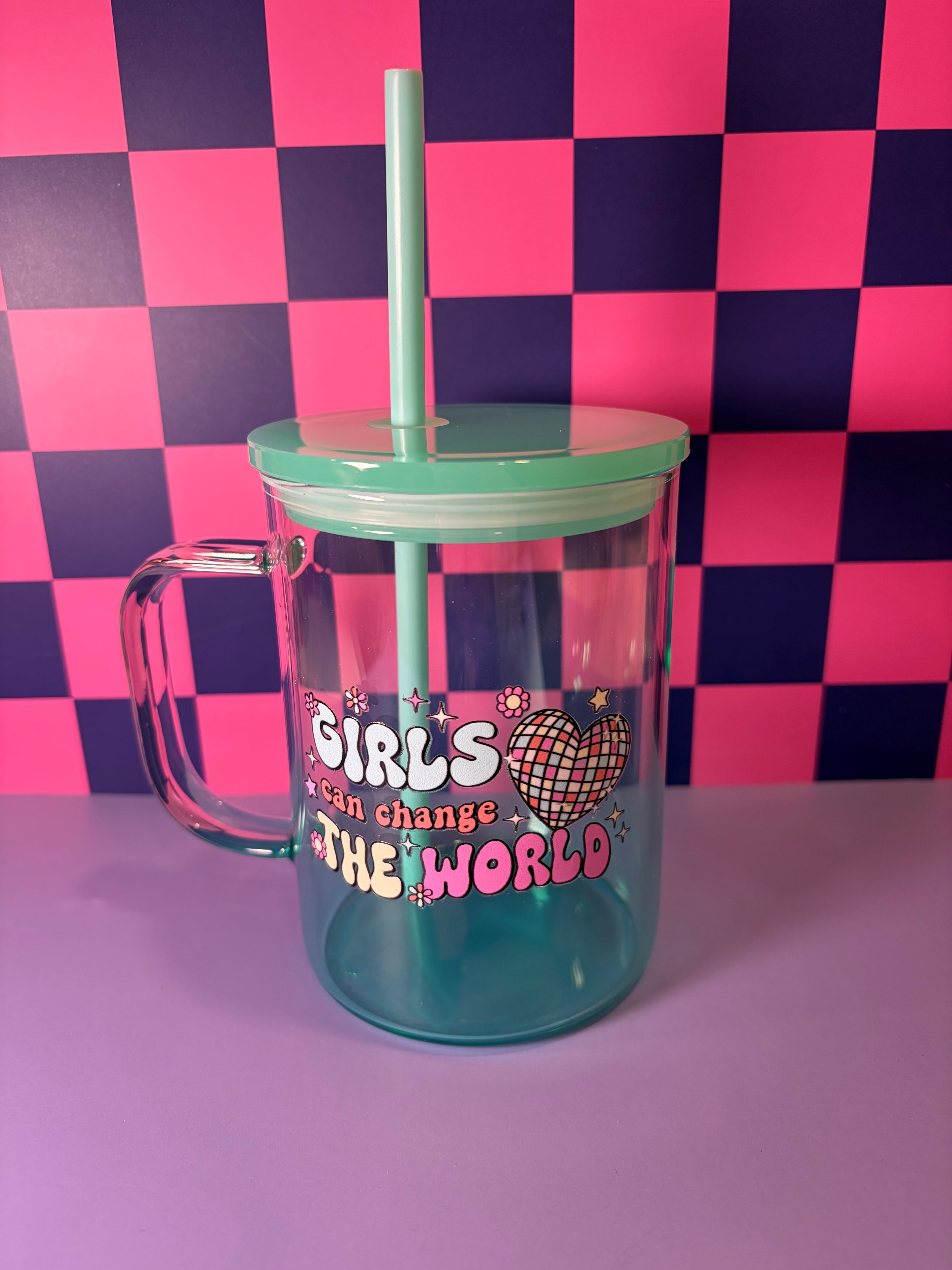 Clear mug with teal green lid and straw and "Girls Can Change the World" colorful disco heart design