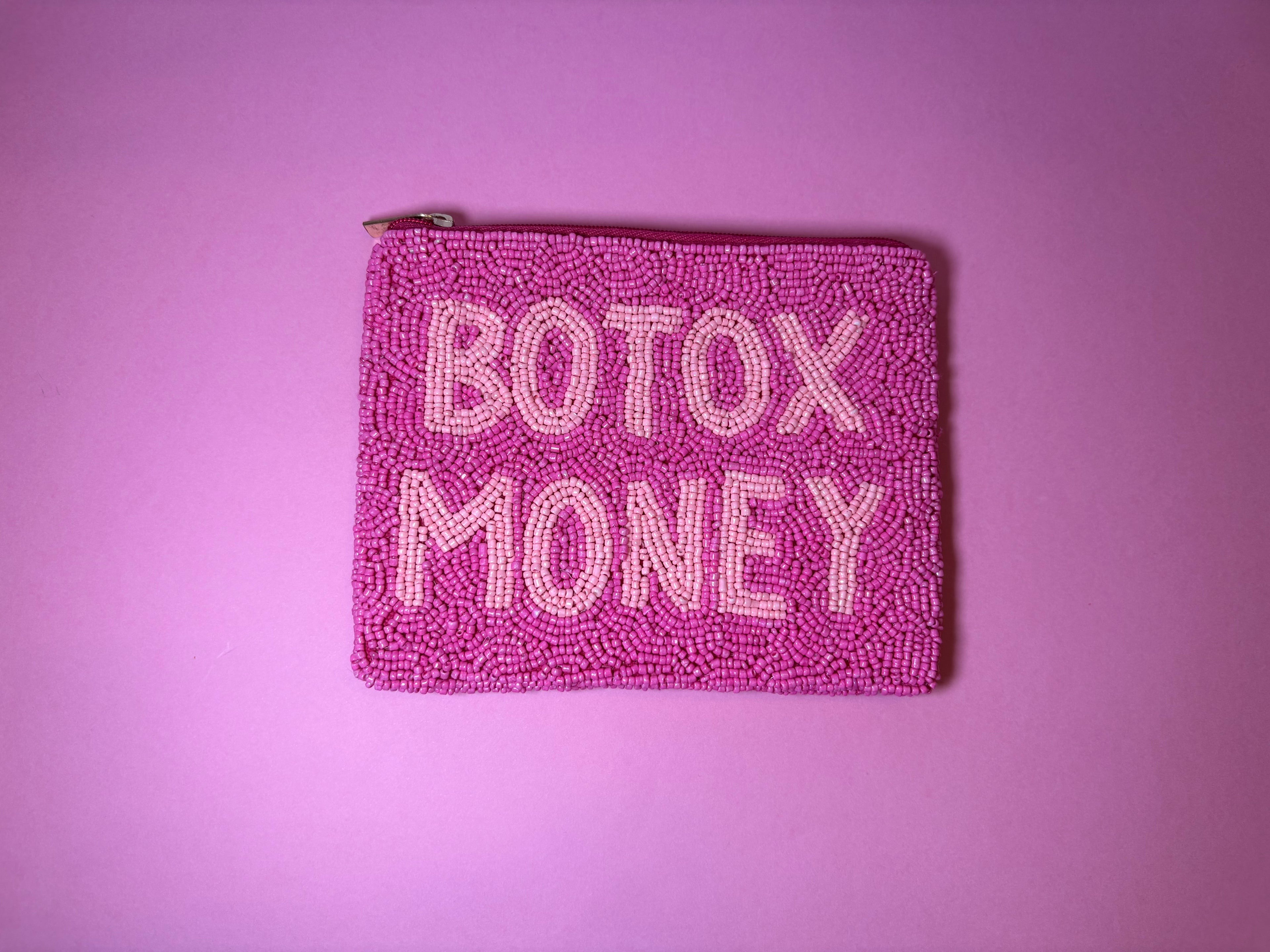A pink beaded zip pouch with the words 'BOTOX MONEY' in light pink lettering, set against a solid pink background.