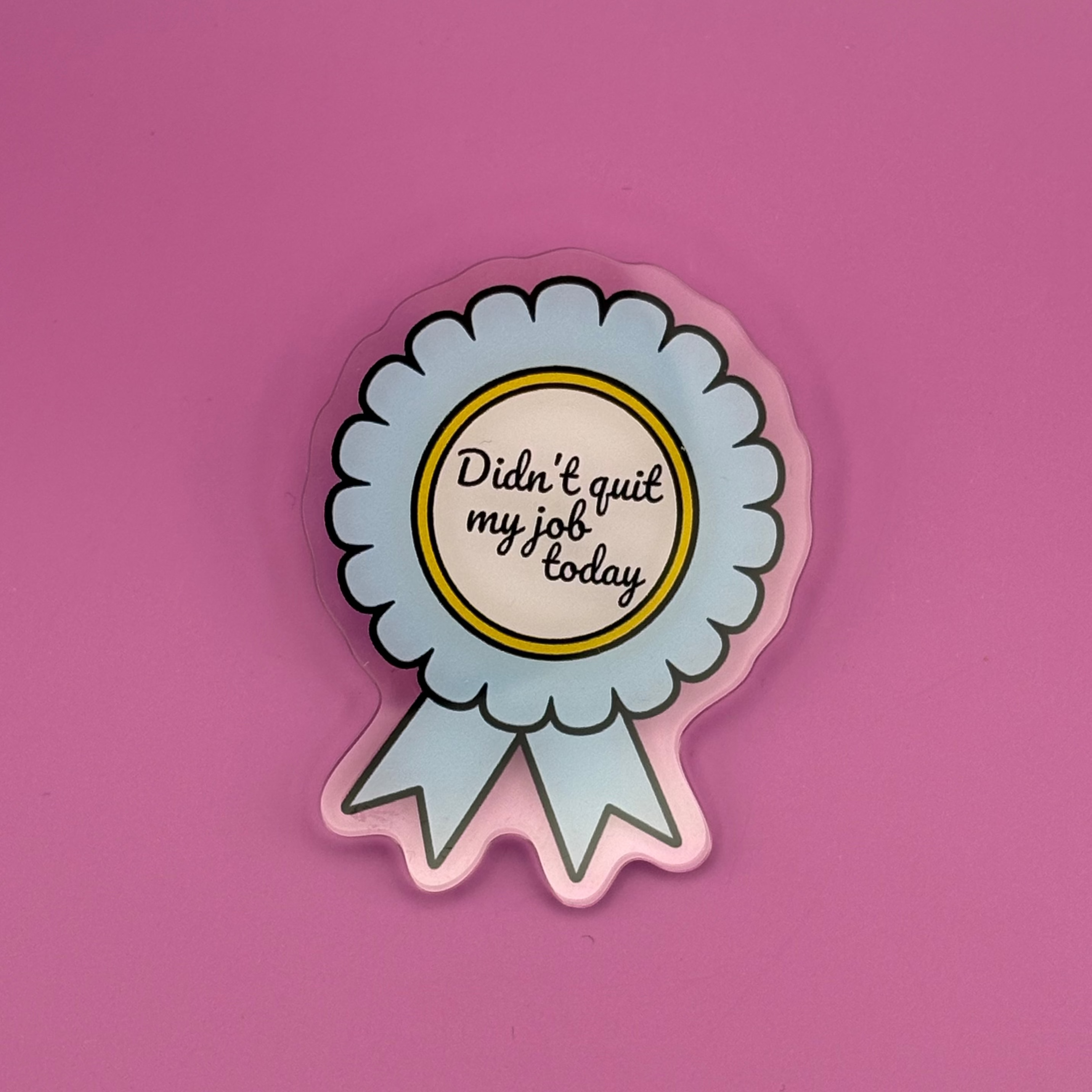 A die-cut sticker shaped like a light blue and white ribbon award badge with a yellow inner circle and black text reading 'Dish * quit my job today', shown on a solid pink background.